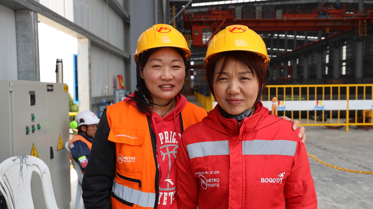 Las dos operadoras chinas sonriendo en el patio de prefabricados del Metro de Bogotá