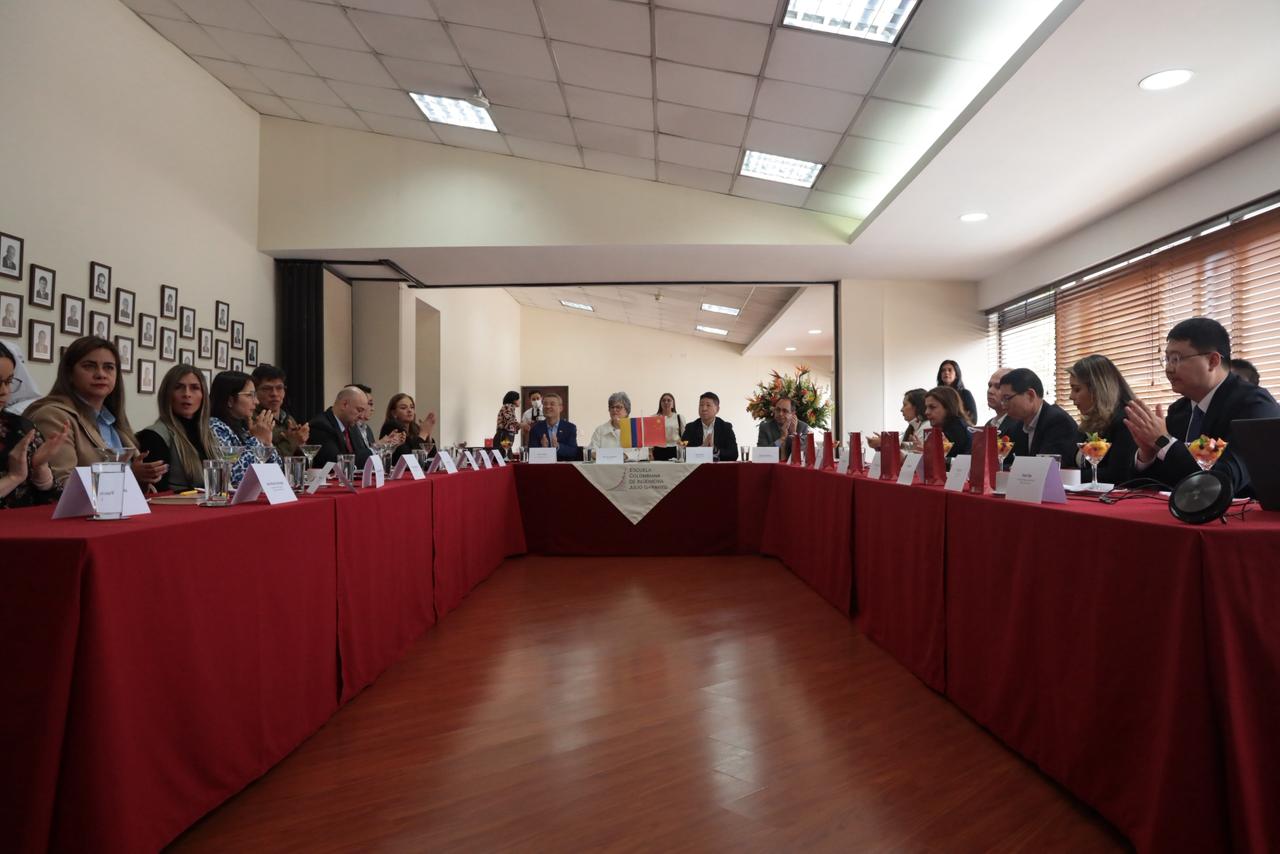 Foto en perspectiva de la mesa en forma de U donde están los participantes de la firma de este convenio