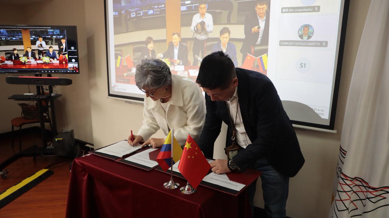 La rectora de la Escuela Colombia de Ingeniería, Myriam Angarita, junto a Ding Wen,  representante legal de Metro Línea 1, firmando sobre una mesa en convenio