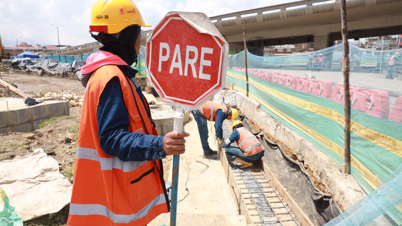 Auxiliar de tráfico en las obras del Metro sosteniendo una señal de PARE