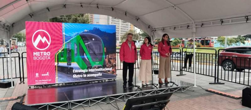 Foto de la tarima con la presentación del evento y el gerente del Metro, la secretaria de Movilidad, y gerente de TransMilenio con micrófonos para hablar al público