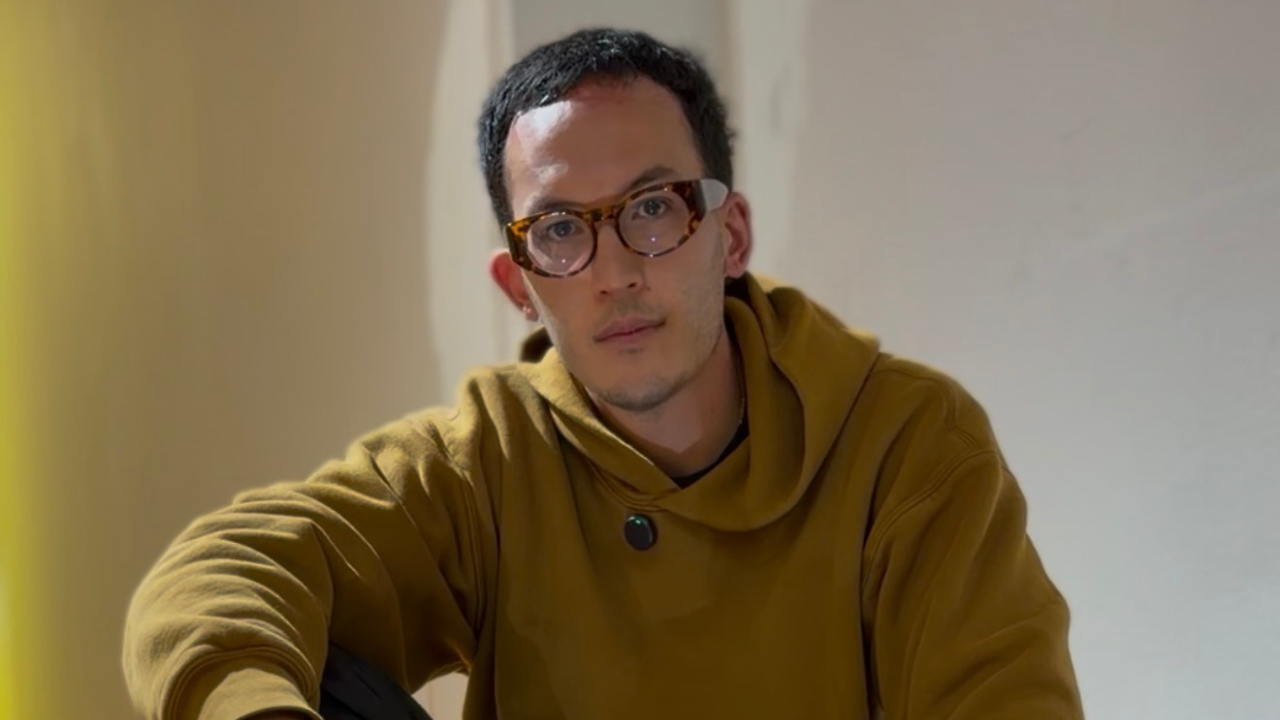 Artista Charly Mai sentado mirando de frente a la cámara